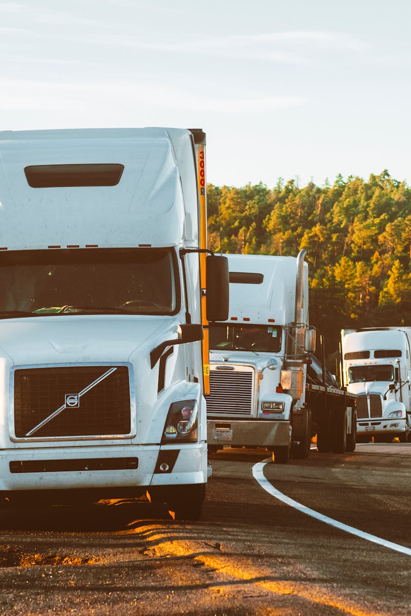 Three semi trucks driving on a highway through a forested landscape in Arizona.
